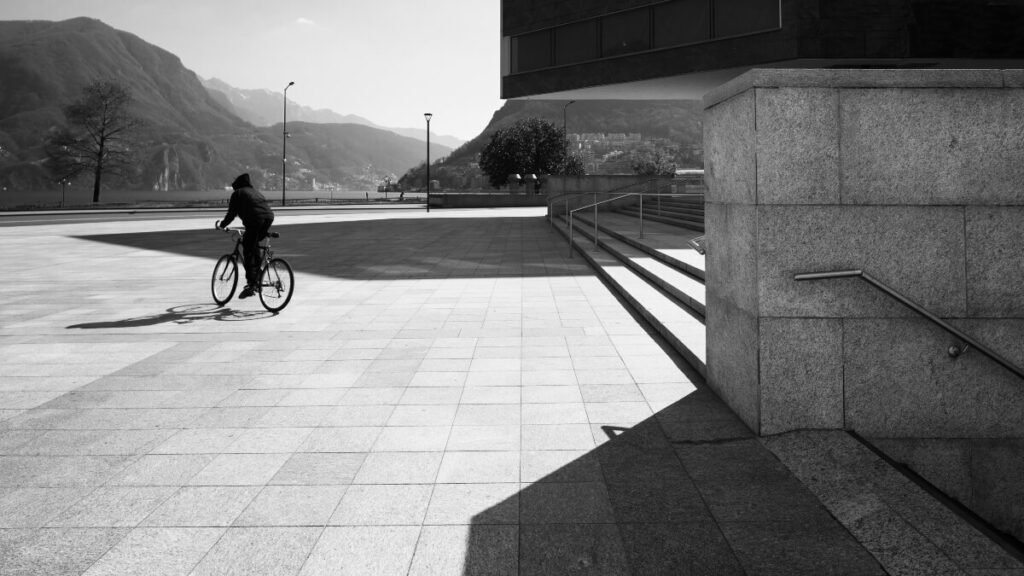 A man rides a bicycle in a large square. Black and white photos
